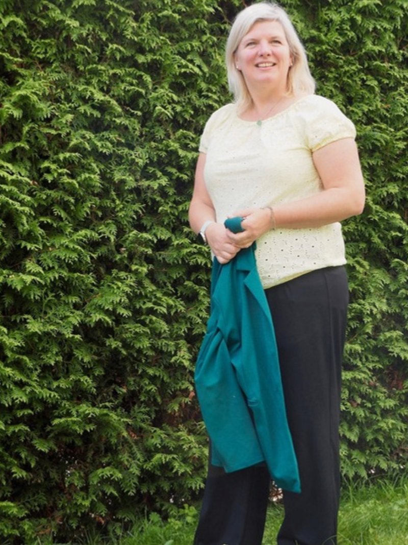 Maartje van Houwelingen staat buiten voor een groene haag