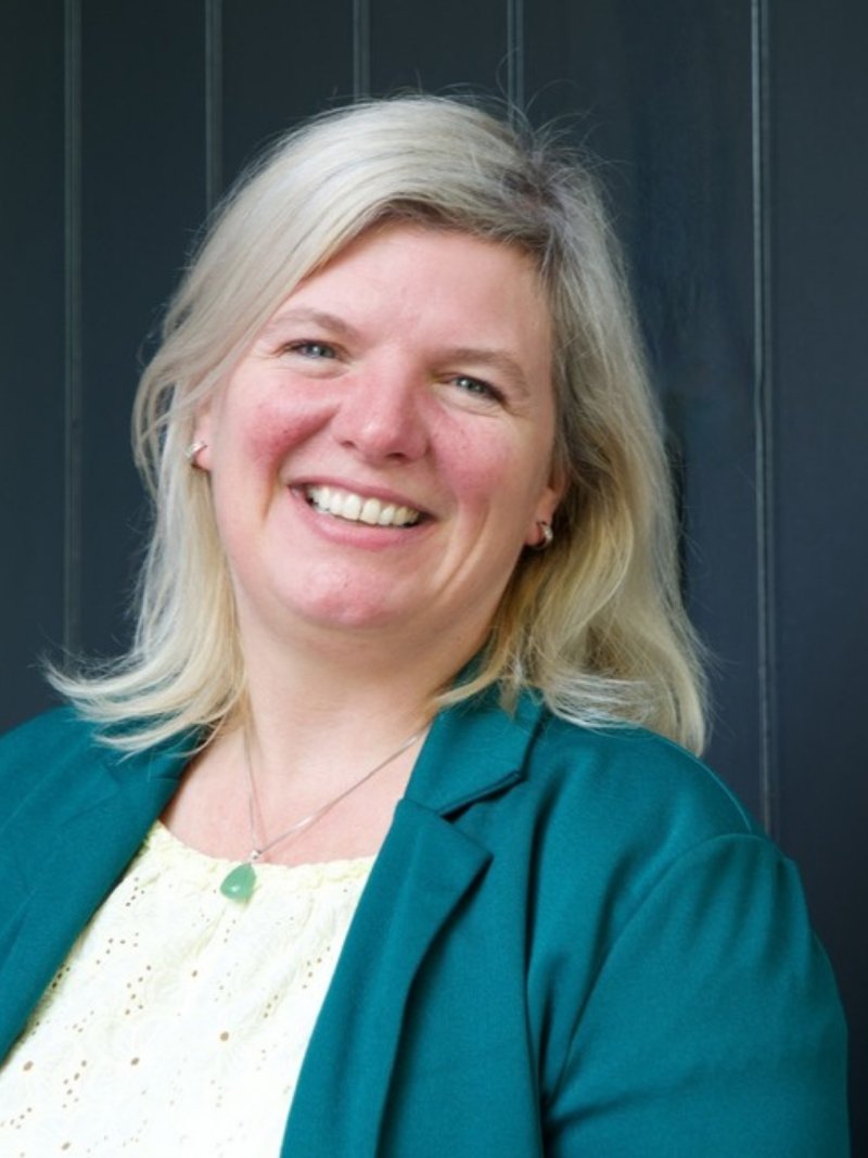 Maartje van Houwelingen, lachend, in een petrolkleurig jasje