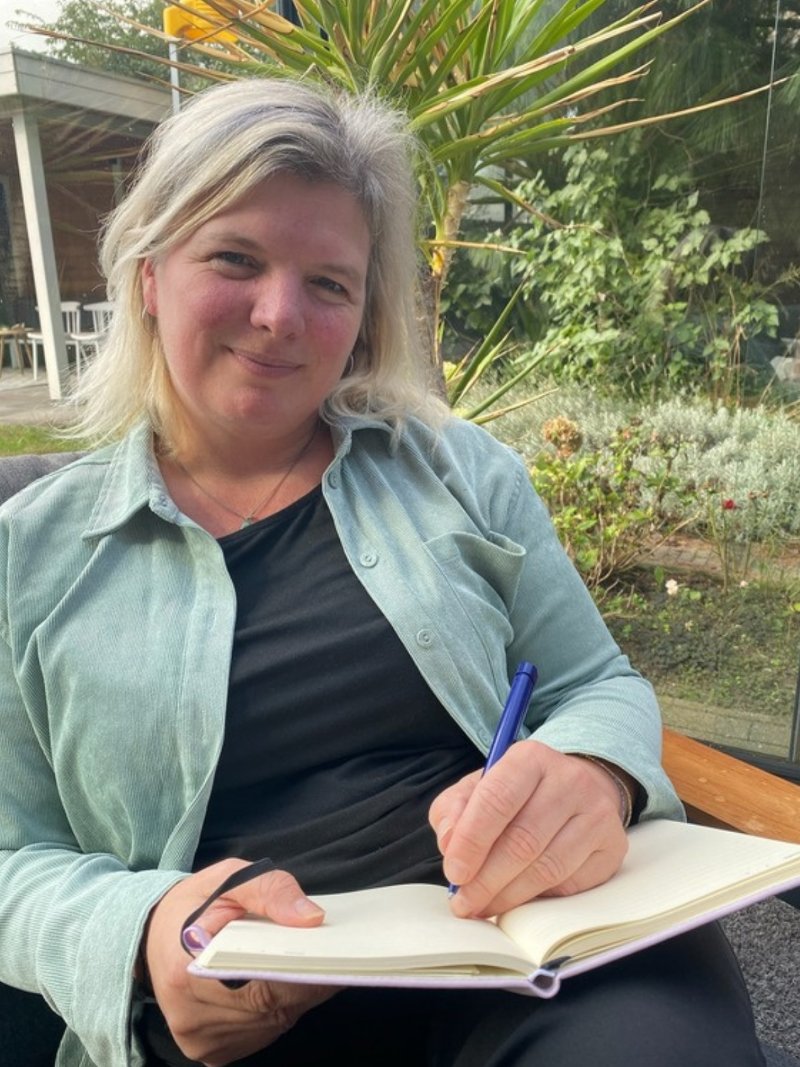 Maartje van Houwelingen schrijft buiten in een notitieboek